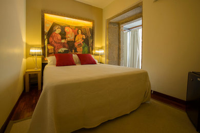 Diseño de dormitorio principal tradicional renovado de tamaño medio sin chimenea con paredes amarillas y suelo de madera en tonos medios