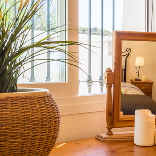 This is an example of a mid-sized mediterranean guest bedroom in Other with beige walls, terra-cotta floors and brown floor.