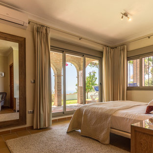 Diseño de dormitorio principal, mediterráneo, de tamaño medio, con paredes beige, suelo de baldosas de cerámica, estufa de leña y suelo beige
