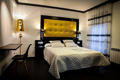 Imagen de habitación de invitados actual de tamaño medio con paredes blancas, suelo de pizarra y suelo negro