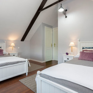 Modelo de habitación de invitados mediterránea, grande, con paredes grises, suelo de madera en tonos medios, suelo marrón, estufa de leña y marco de chimenea de baldosas y/o azulejos