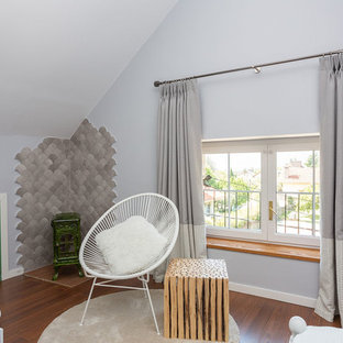 Foto de habitación de invitados mediterránea, grande, con paredes grises, suelo de madera en tonos medios, suelo marrón, estufa de leña y marco de chimenea de baldosas y/o azulejos
