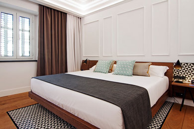 Modelo de dormitorio principal tradicional renovado grande sin chimenea con paredes blancas y suelo de madera en tonos medios