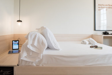 Modelo de dormitorio actual pequeño con paredes blancas, suelo laminado y suelo gris