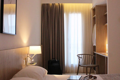 Imagen de dormitorio contemporáneo pequeño con paredes blancas, suelo de baldosas de porcelana y suelo marrón