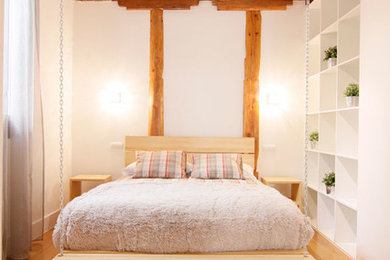 Imagen de dormitorio principal rural pequeño sin chimenea con paredes beige y suelo de madera en tonos medios