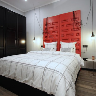 Foto de dormitorio industrial con paredes grises, suelo de madera oscura y suelo marrón