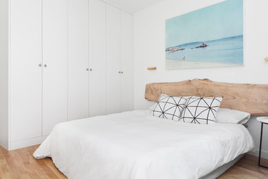 Imagen de dormitorio principal marinero con paredes blancas, suelo de madera clara y suelo beige