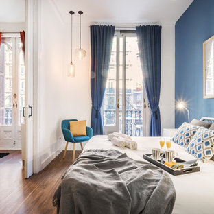 Modelo de dormitorio principal, actual, con paredes blancas, suelo de madera en tonos medios y suelo marrón