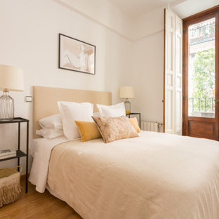 Imagen de dormitorio mediterráneo con paredes blancas, suelo de madera en tonos medios y suelo marrón