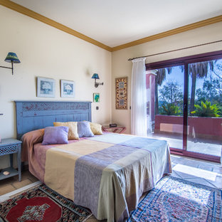 Diseño de dormitorio principal, bohemio, de tamaño medio, sin chimenea, con suelo de baldosas de terracota y paredes amarillas