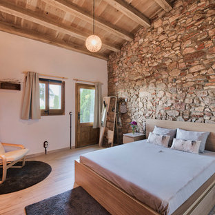 Modelo de dormitorio rústico, sin chimenea, con paredes blancas y suelo de madera clara