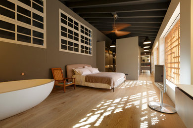 Modelo de dormitorio principal urbano extra grande sin chimenea con paredes beige y suelo de madera en tonos medios