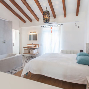 Ejemplo de dormitorio principal, mediterráneo, de tamaño medio, con paredes blancas, suelo de madera en tonos medios y suelo marrón