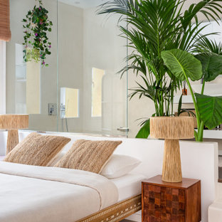 Modelo de dormitorio tropical con paredes beige, suelo de madera oscura y suelo marrón