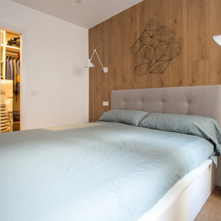 Imagen de dormitorio principal, escandinavo, de tamaño medio, sin chimenea, con paredes blancas, suelo de madera en tonos medios y suelo marrón