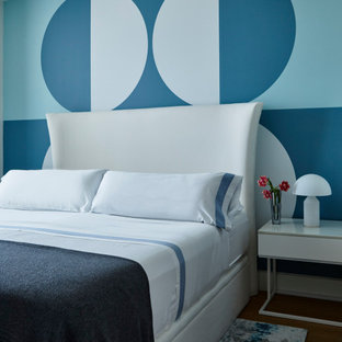 Foto de dormitorio contemporáneo con paredes azules, suelo de madera en tonos medios y suelo marrón