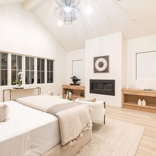 Immagine di una grande camera matrimoniale design con pareti bianche, parquet chiaro, camino sospeso, cornice del camino in legno e pavimento beige