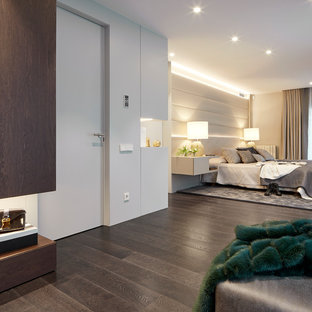 Modelo de dormitorio principal, contemporáneo, con paredes blancas, suelo de madera oscura y suelo marrón