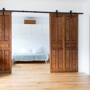 Modelo de dormitorio principal, escandinavo, de tamaño medio, sin chimenea, con paredes blancas, suelo de madera clara y suelo beige