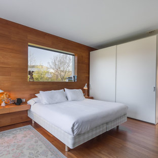 Modelo de dormitorio contemporáneo con paredes marrones, suelo de madera en tonos medios y suelo marrón