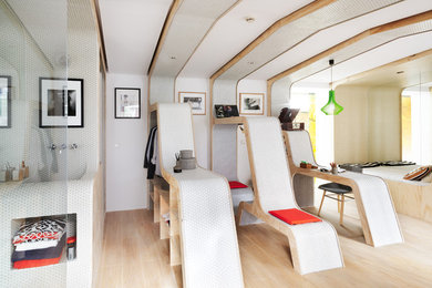 Imagen de dormitorio tipo loft actual de tamaño medio sin chimenea con paredes blancas y suelo de madera clara