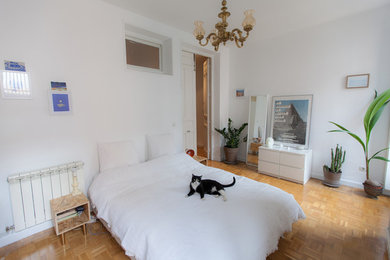 Imagen de dormitorio principal retro de tamaño medio sin chimenea con paredes blancas y suelo de madera en tonos medios