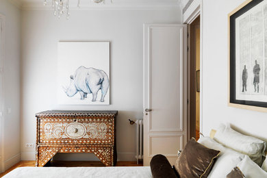 Medium sized bedroom in Madrid with white walls and medium hardwood flooring.