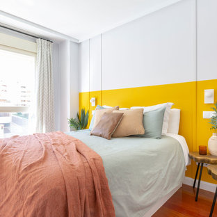 Foto de habitación de invitados actual con paredes amarillas y suelo de madera en tonos medios