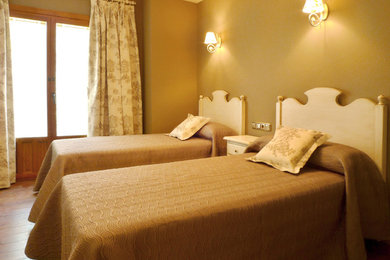 Diseño de habitación de invitados clásica renovada de tamaño medio sin chimenea con paredes amarillas y suelo de madera en tonos medios