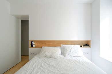 Modelo de dormitorio principal escandinavo de tamaño medio sin chimenea con paredes blancas y suelo de madera clara