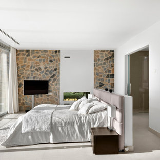 Foto de dormitorio principal, contemporáneo, grande, con paredes blancas, suelo de baldosas de porcelana, chimenea lineal, marco de chimenea de yeso y suelo beige
