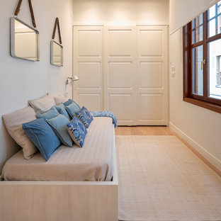 Modelo de habitación de invitados actual, de tamaño medio, sin chimenea, con paredes blancas, suelo de madera en tonos medios y suelo marrón