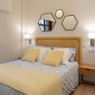 Diseño de dormitorio contemporáneo, de tamaño medio, sin chimenea, con paredes blancas, suelo laminado y suelo marrón