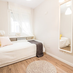 Ejemplo de habitación de invitados actual, pequeña, con suelo laminado, paredes beige y suelo beige
