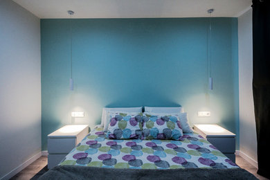Modelo de dormitorio principal moderno pequeño con paredes verdes, suelo laminado y suelo marrón