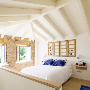 Imagen de dormitorio mediterráneo con paredes blancas, suelo de madera en tonos medios y suelo marrón