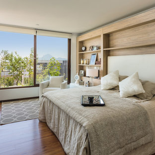 Modelo de dormitorio principal, contemporáneo, grande, con suelo de madera oscura, paredes beige y suelo marrón