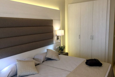 Imagen de dormitorio moderno de tamaño medio con paredes beige y suelo laminado