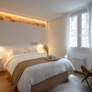 Imagen de dormitorio contemporáneo con paredes blancas, suelo de madera clara y suelo beige
