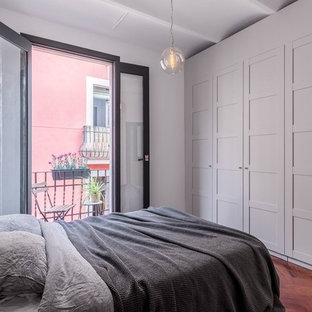 Modelo de dormitorio principal, actual, sin chimenea, con paredes blancas y suelo de madera en tonos medios