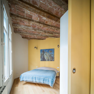 Foto de dormitorio principal, industrial, de tamaño medio, sin chimenea, con paredes amarillas y suelo de madera en tonos medios