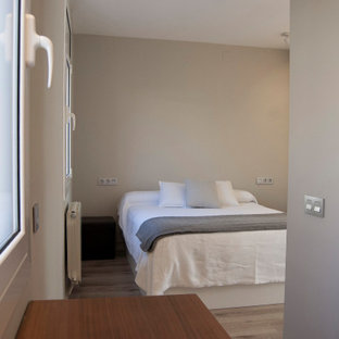 Ejemplo de dormitorio principal, contemporáneo, de tamaño medio, con paredes grises, suelo laminado, chimeneas suspendidas y marco de chimenea de metal