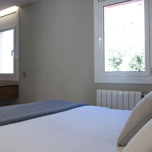 Modelo de dormitorio principal, contemporáneo, de tamaño medio, con paredes grises, suelo laminado, chimeneas suspendidas y marco de chimenea de metal