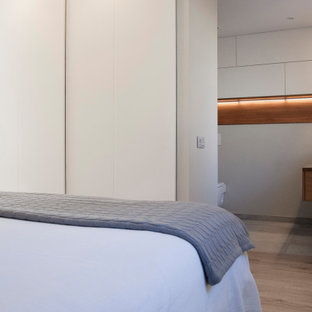 Ejemplo de dormitorio principal, actual, de tamaño medio, con paredes grises, suelo laminado, chimeneas suspendidas y marco de chimenea de metal