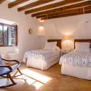 Imagen de habitación de invitados mediterránea, grande, sin chimenea, con paredes blancas y suelo de baldosas de terracota