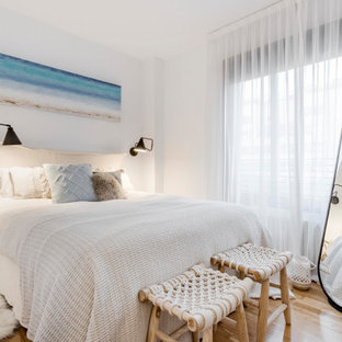 Foto de dormitorio principal, marinero, pequeño, sin chimenea, con paredes blancas, suelo de madera en tonos medios y suelo marrón