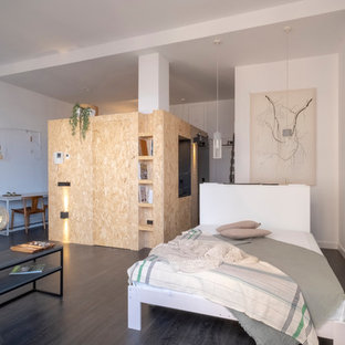 Foto de dormitorio urbano con paredes blancas, suelo de madera oscura y suelo marrón