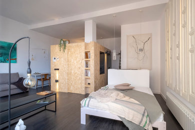 Foto de dormitorio urbano con paredes blancas, suelo de madera oscura y suelo marrón