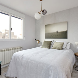 Ejemplo de habitación de invitados actual con paredes grises, suelo de madera clara y suelo gris